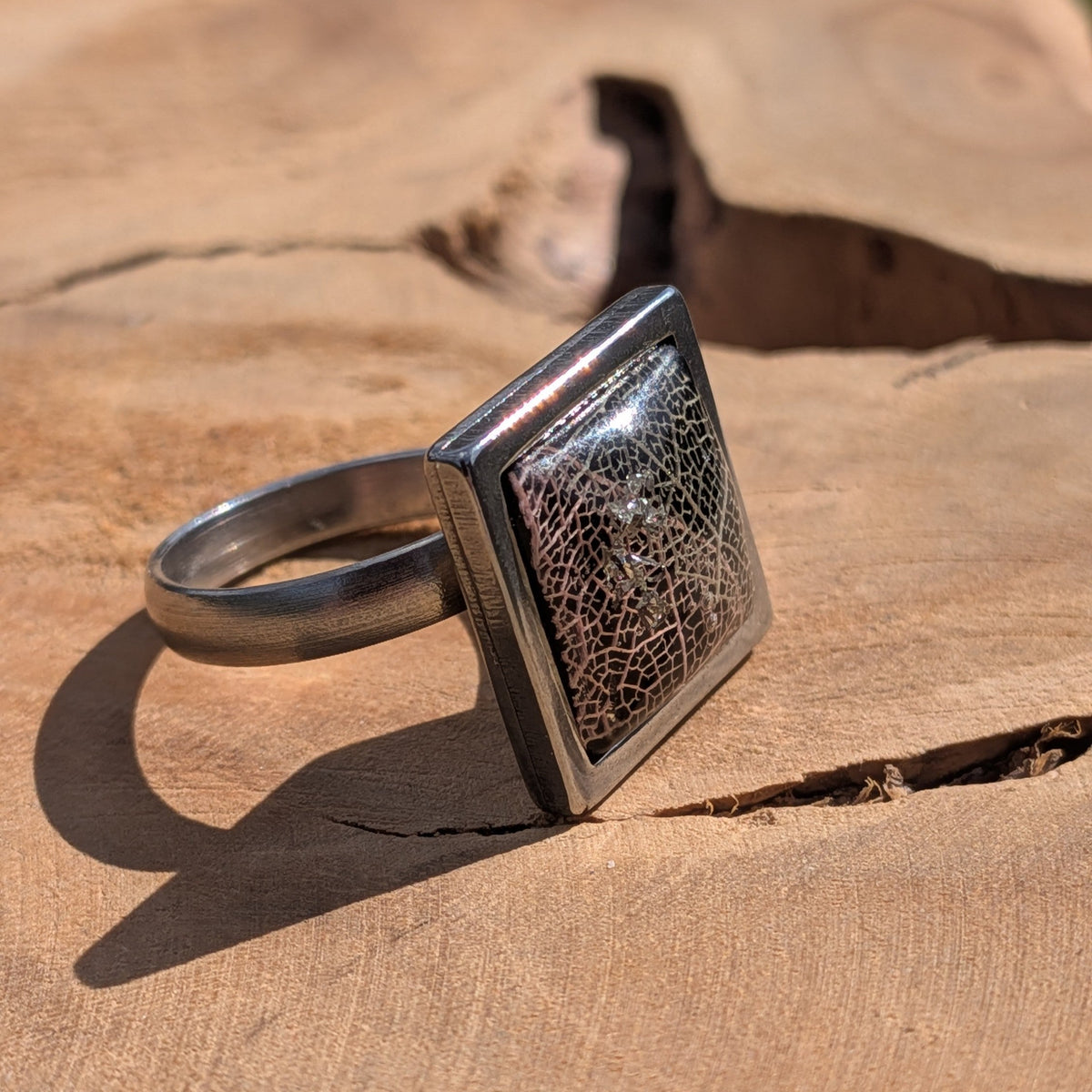 Front view of black skeleton leaf resin ring on wood, 15×15mm square steel bezel – EL-Creations