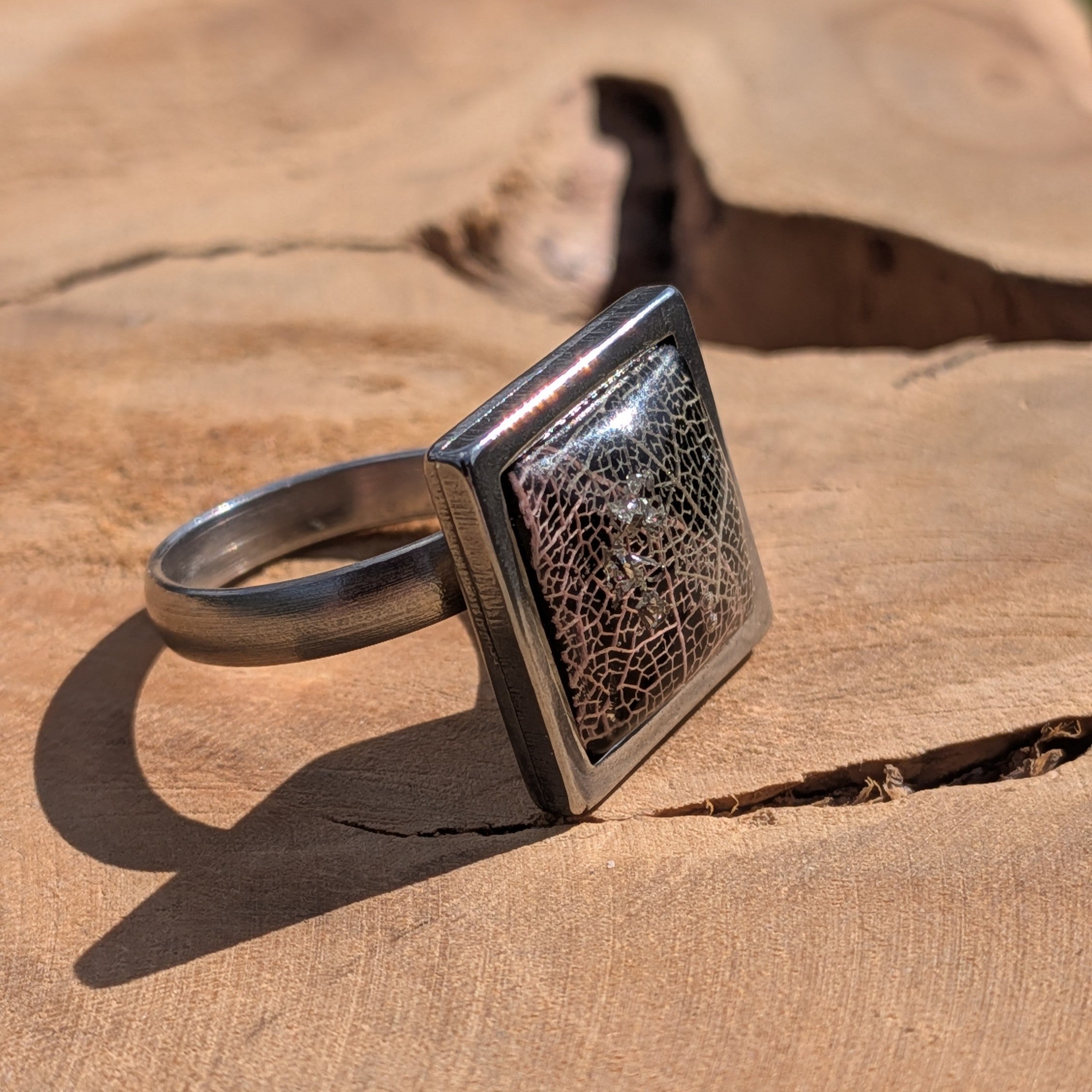 Front view of black skeleton leaf resin ring on wood, 15×15mm square steel bezel – EL-Creations