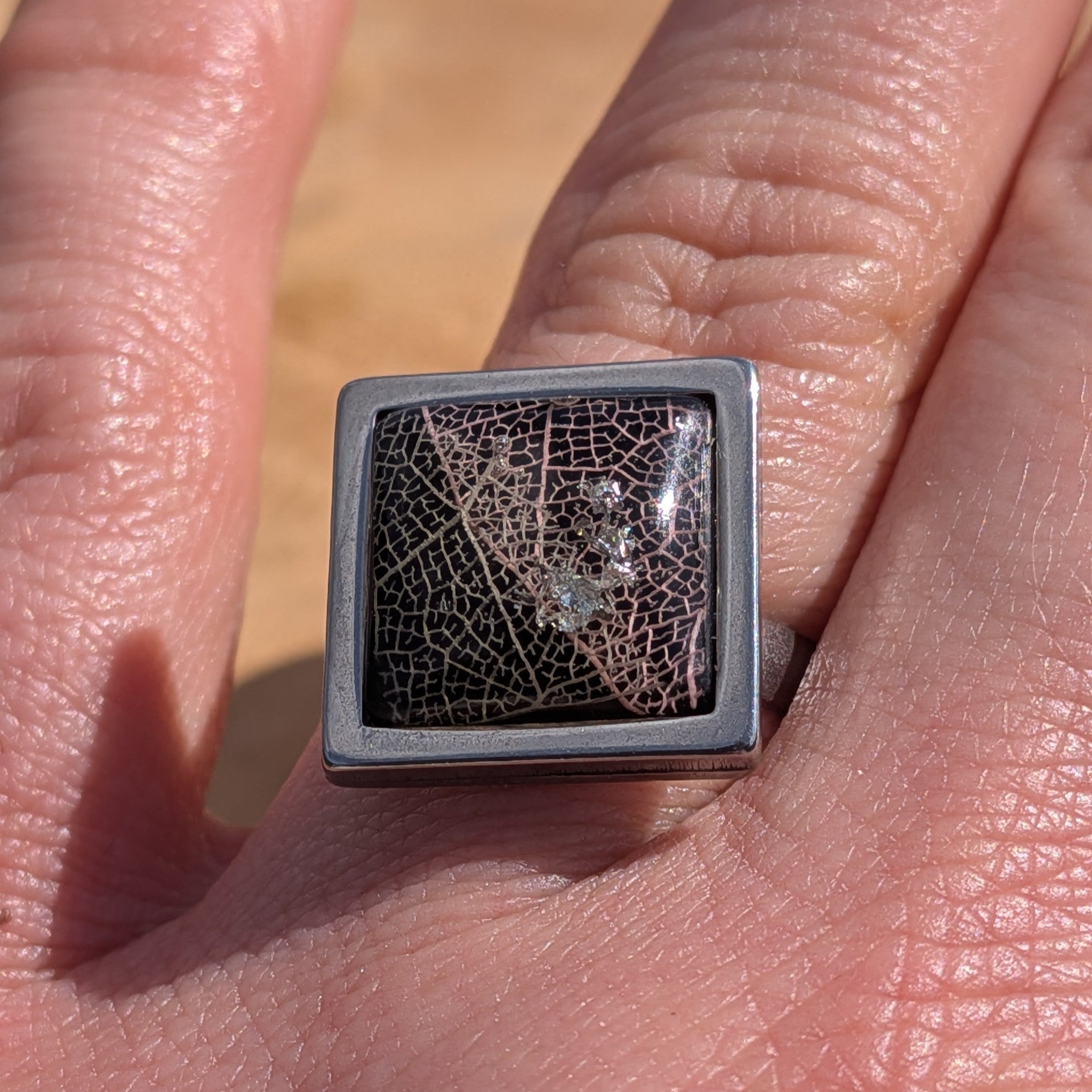 Top view of black resin ring on hand, skeleton leaf detail in 15mm square stainless steel setting – EL-Creations