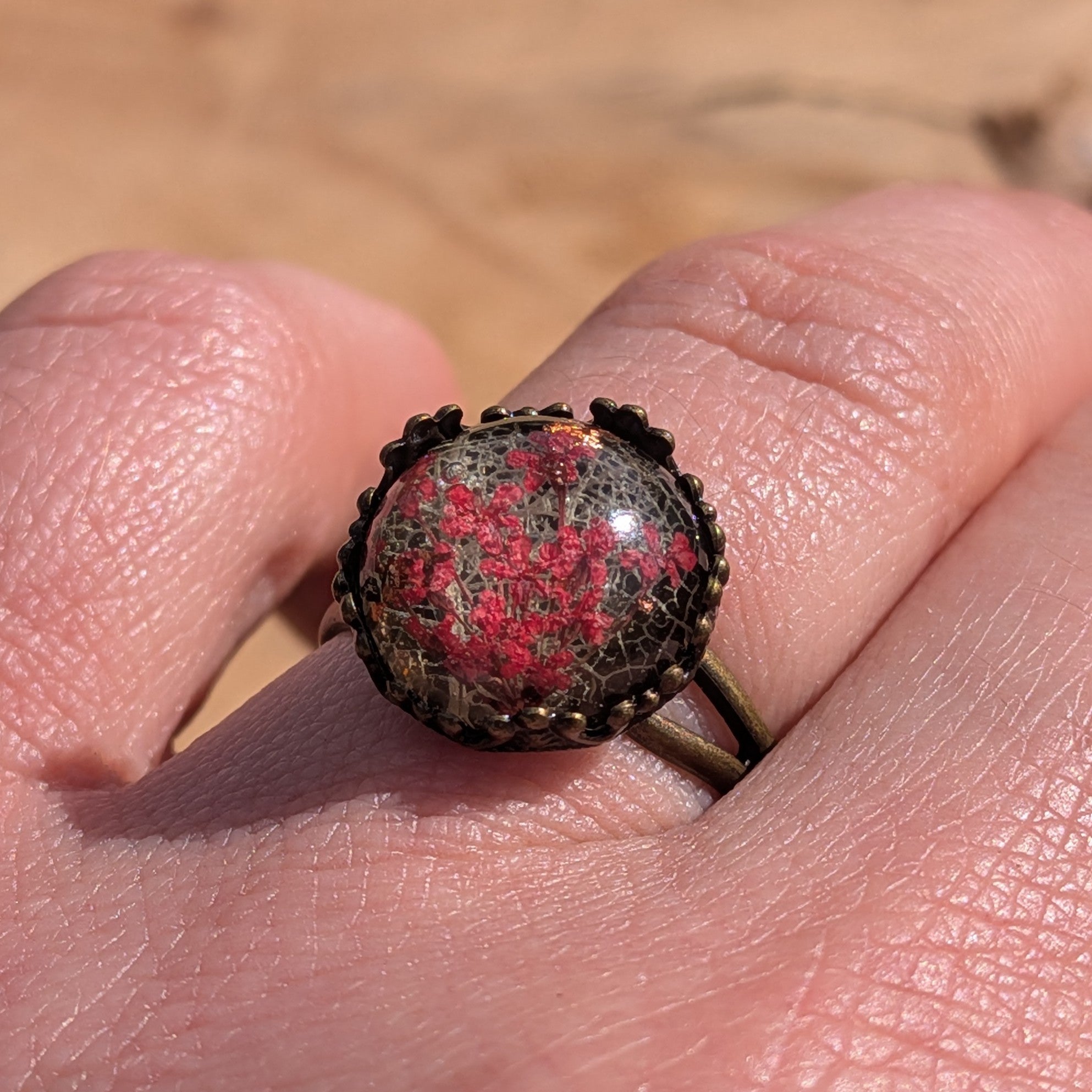 Botanical resin ring on hand, top view of red Queen Anne's Lace and skeleton leaf in antique bronze bezel – EL-Creations
