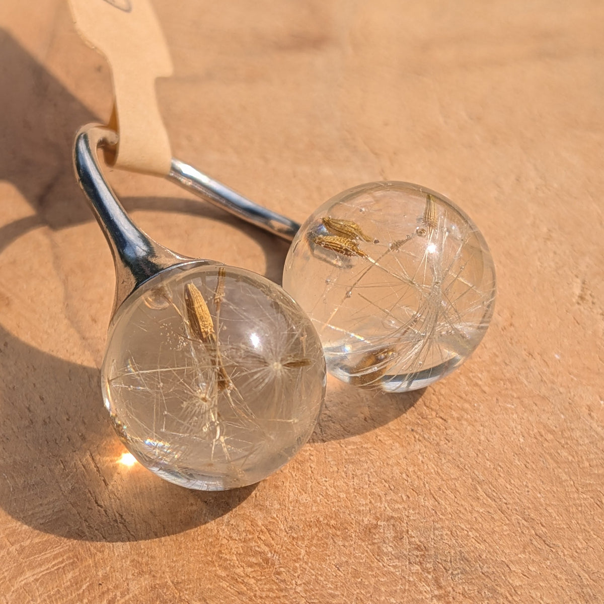 Close-up of dandelion seeds inside clear resin sphere ring, EL-Creations