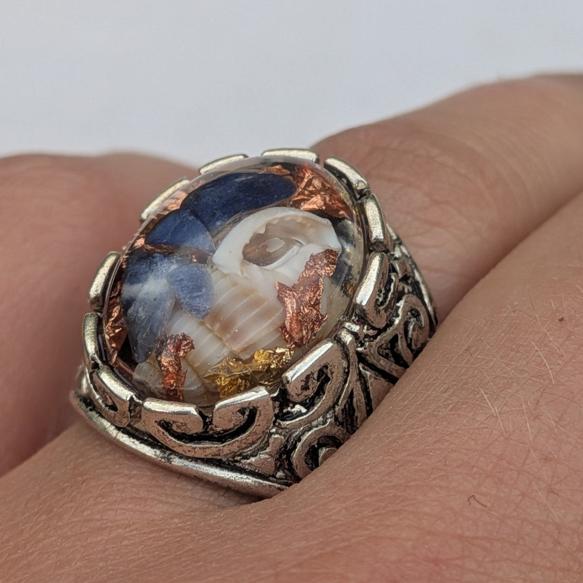 Sodalite shell copper flakes resin oval statement ring angled view on wooden surface – EL-Creations