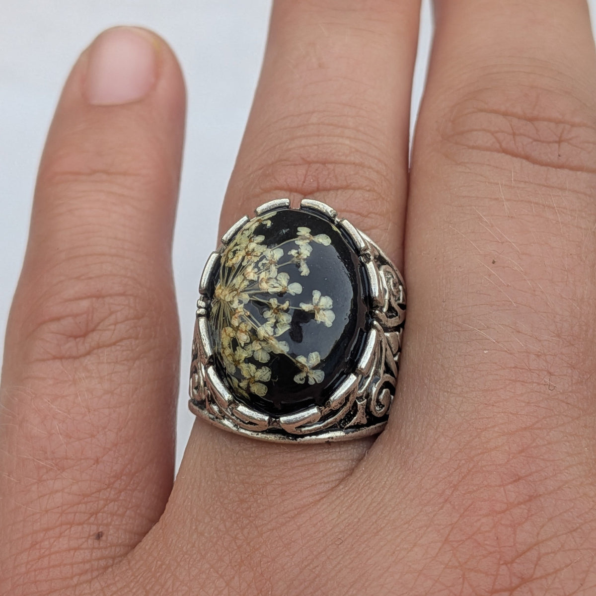 Queen Anne's Lace black resin oval ring with ornate silver filigree band flat lay on wood – EL-Creations