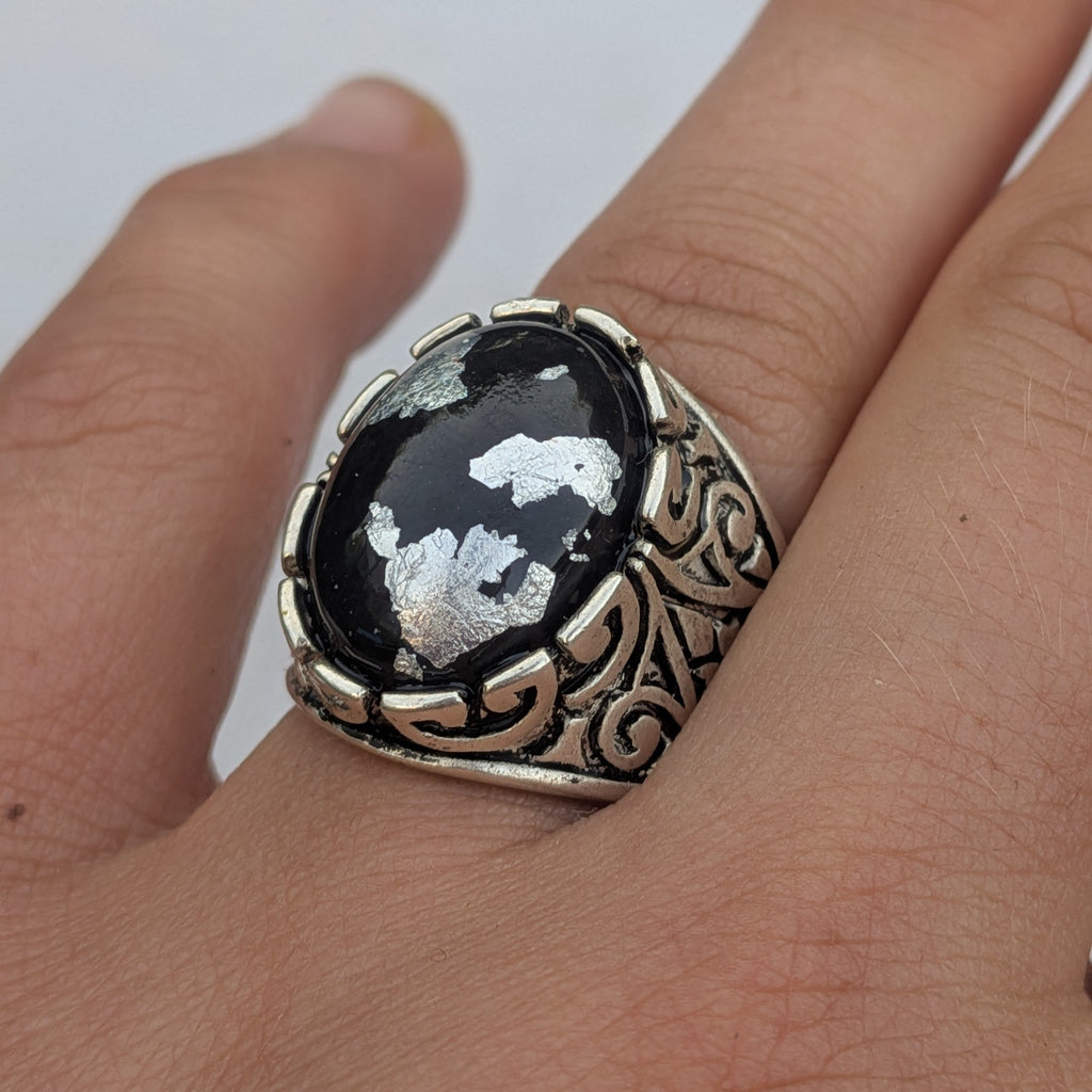 Black resin oval statement ring with silver flakes worn on hand close-up white background – EL-Creations