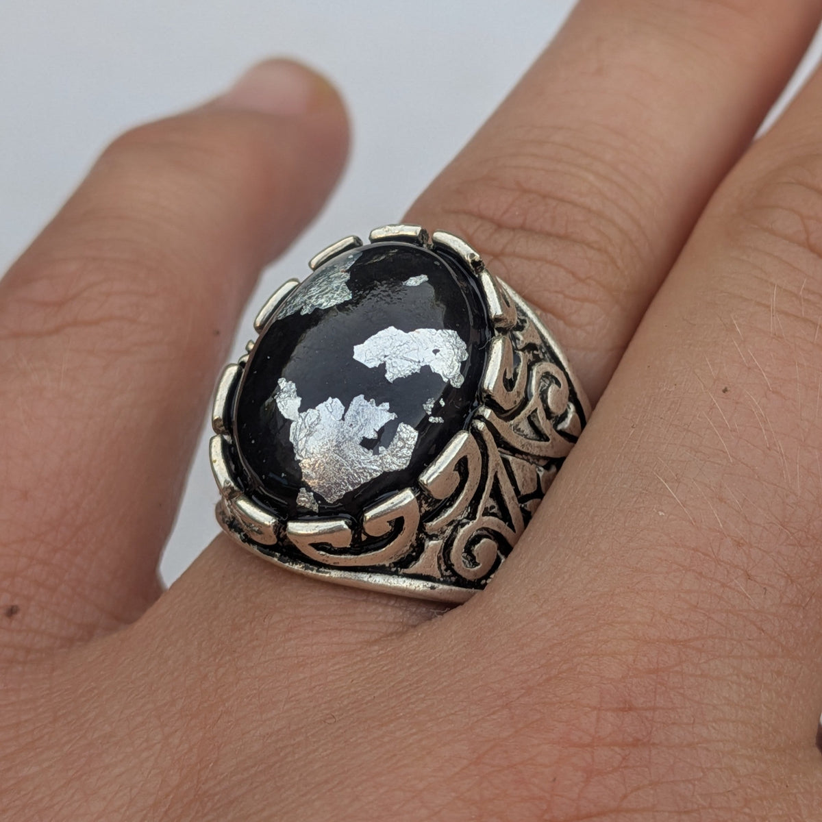 Black resin oval statement ring with silver flakes worn on hand close-up white background – EL-Creations