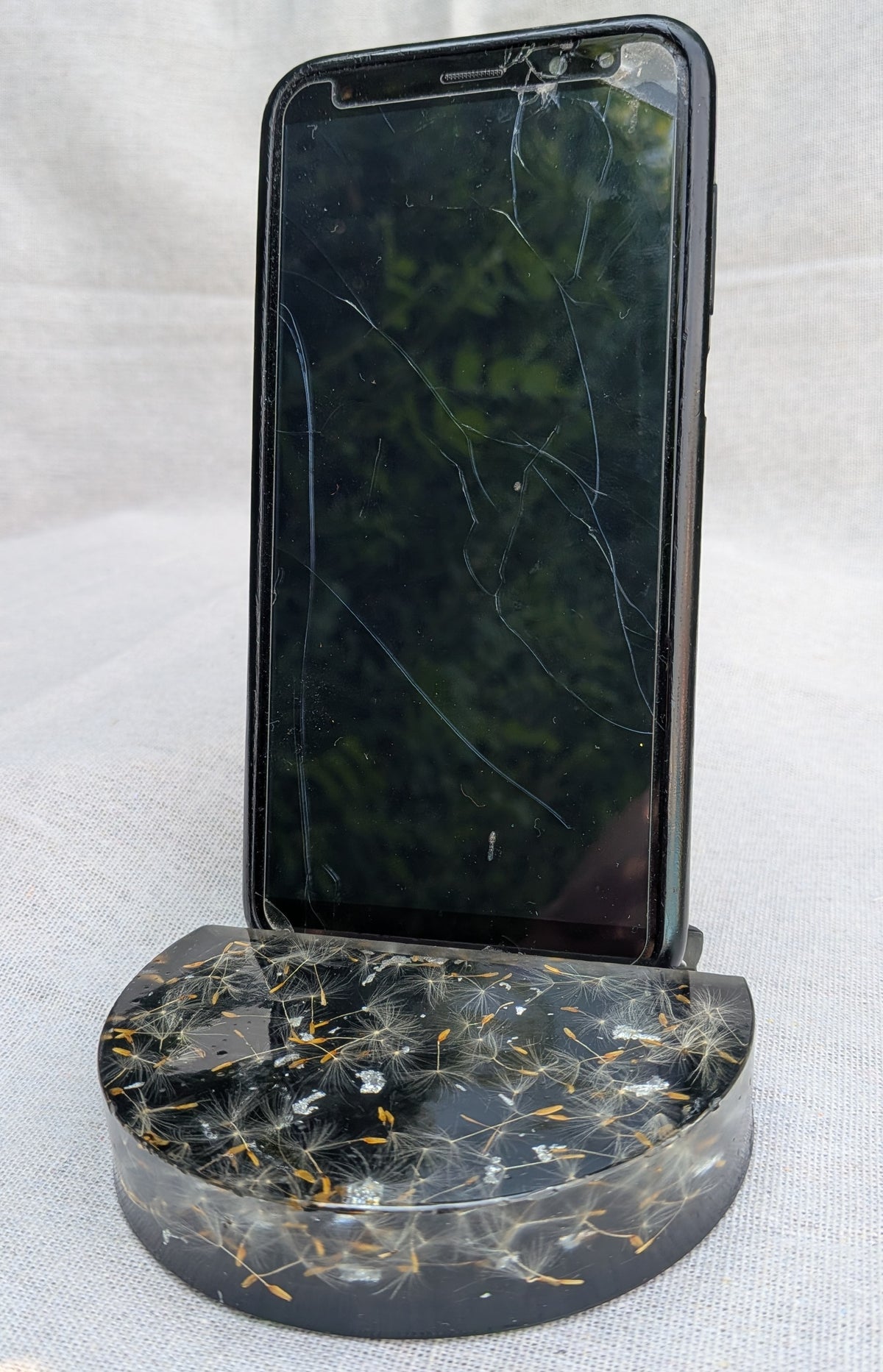 Smartphone resting in dandelion resin stand – handcrafted botanical desk accessory, 10cm diameter – EL-CreationS