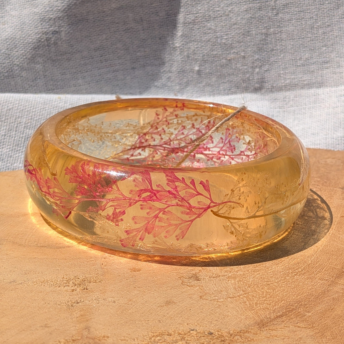 Amber gold resin fern bangle bracelet worn on wrist in sunlight by EL-Creations