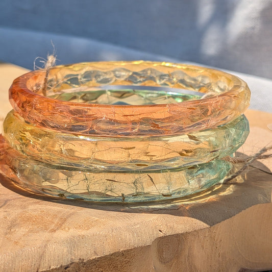 Green and yellow ombre dandelion resin bangle held to the light by EL-Creations