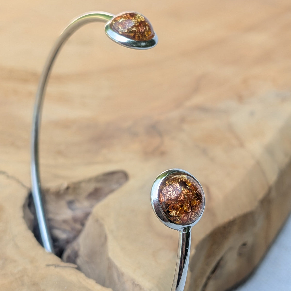 Handmade amber gold resin cuff bracelet side view on driftwood – EL-Creations