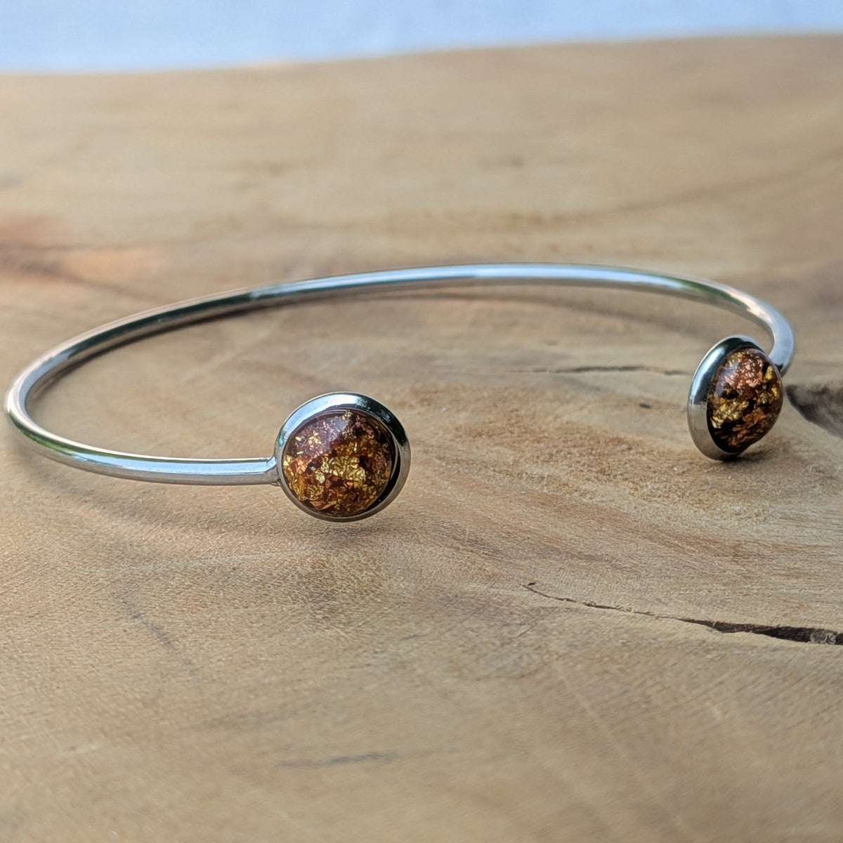 Two amber gold resin stainless steel cuff bracelets flat lay on wood – EL-Creations