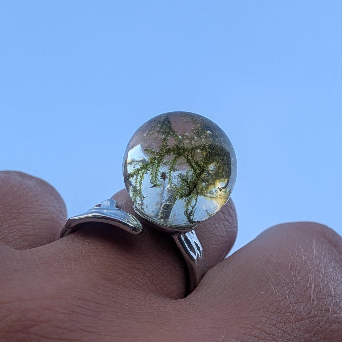 Moss resin ring held against blue sky – real forest moss in 15mm sphere – EL-CreationS