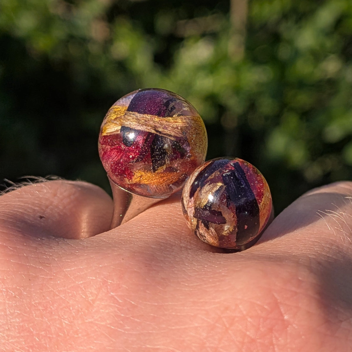 Two resin spheres with tulip petals close-up front view on fingers – EL-Creations