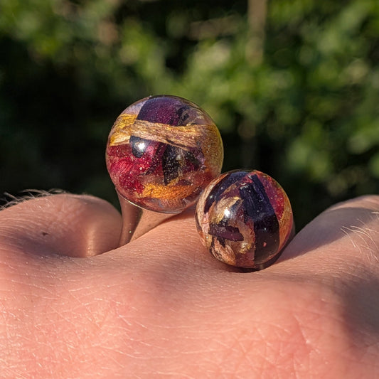 Two resin spheres with tulip petals close-up front view on fingers – EL-Creations
