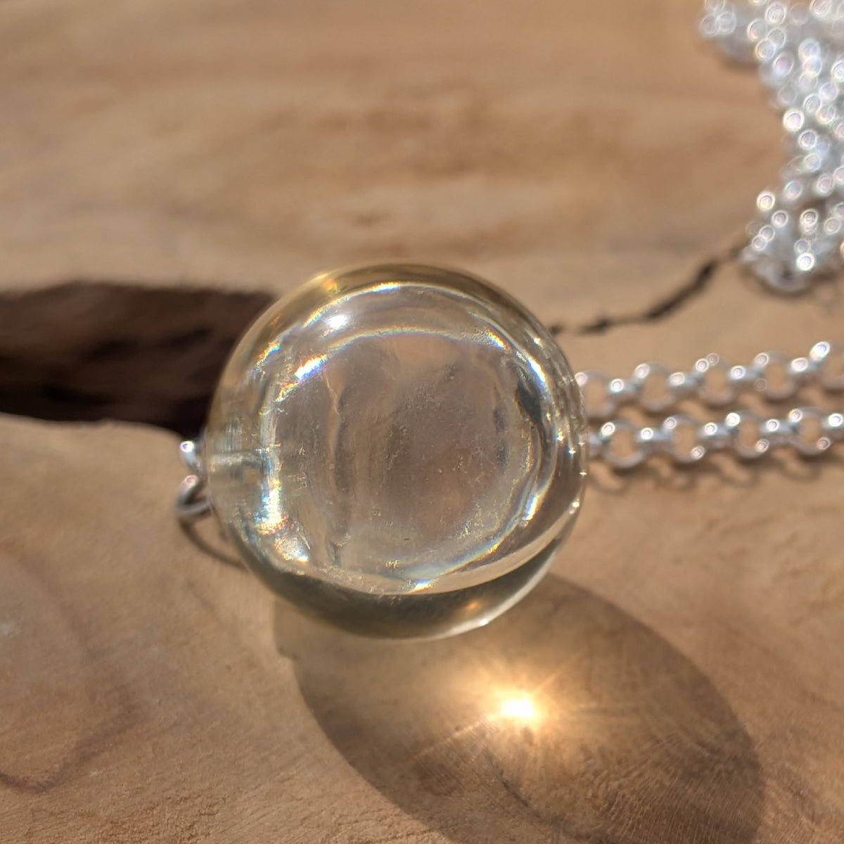 Clear resin ball pendant necklace against bright sky — handmade resin jewelry EL-CreationS Belgium