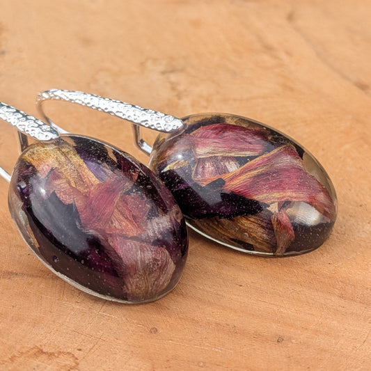 Resin botanical drop earrings with dried tulip petals in burgundy gold purple angled view on wood – EL-Creations