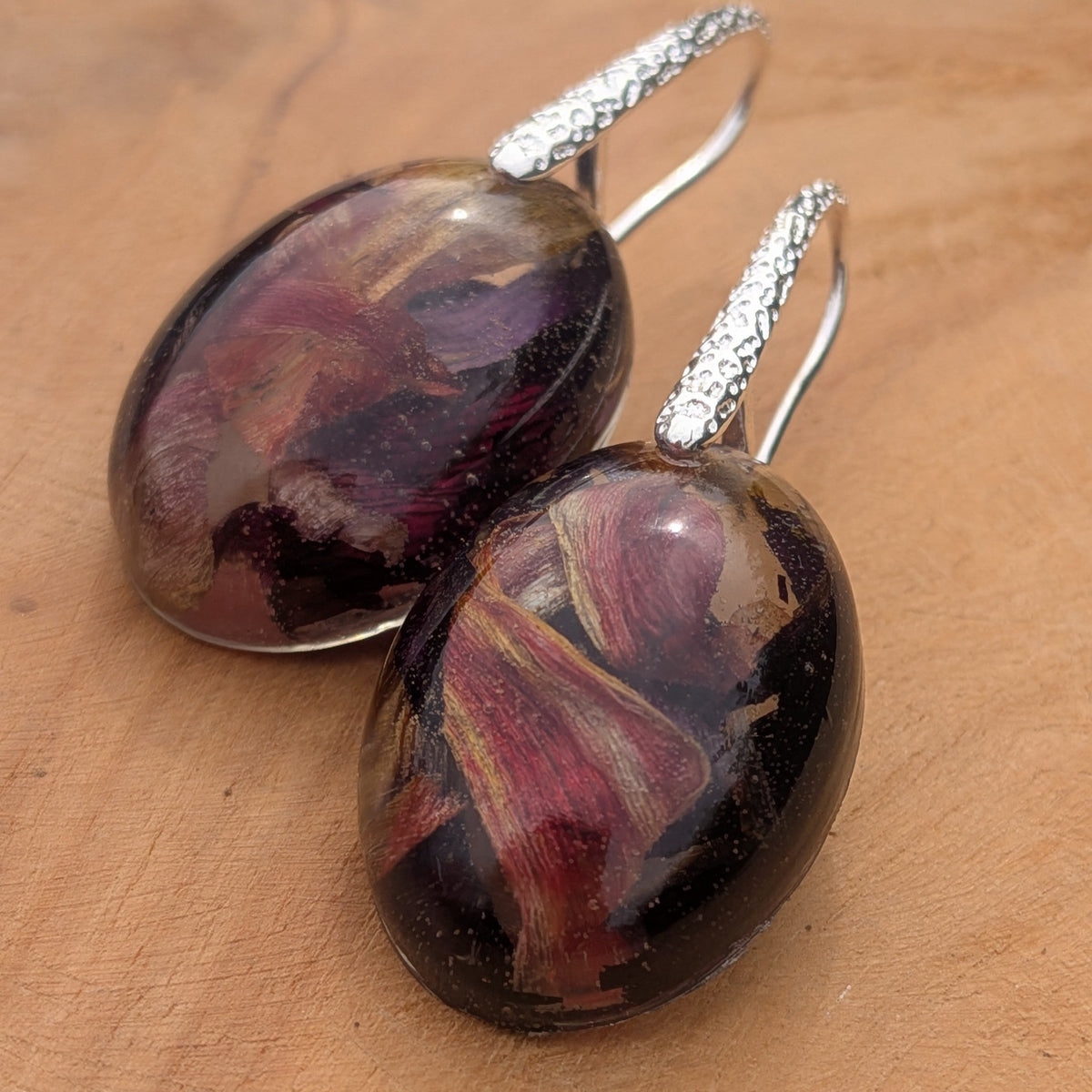 Oval resin earrings with real tulip petals  background close-up showing hook detail on wood – EL-Creations