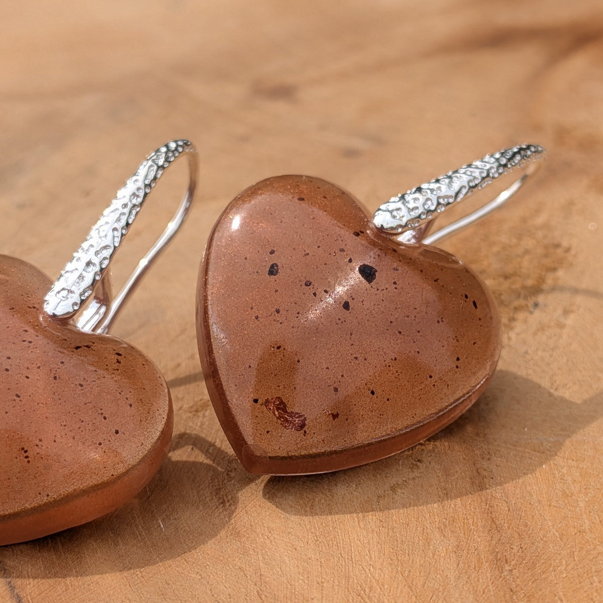 Bold heart-shaped resin drop earrings warm brown copper flakes close-up showing high-gloss dome on wood – EL-Creations