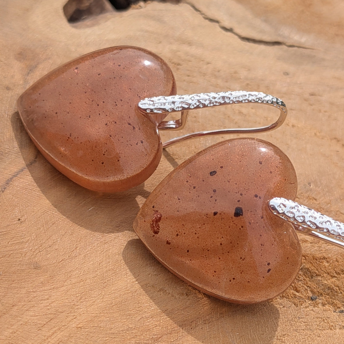 Brown resin heart statement earrings angled view showing sculptural shape and silver hook detail on wood – EL-Creations