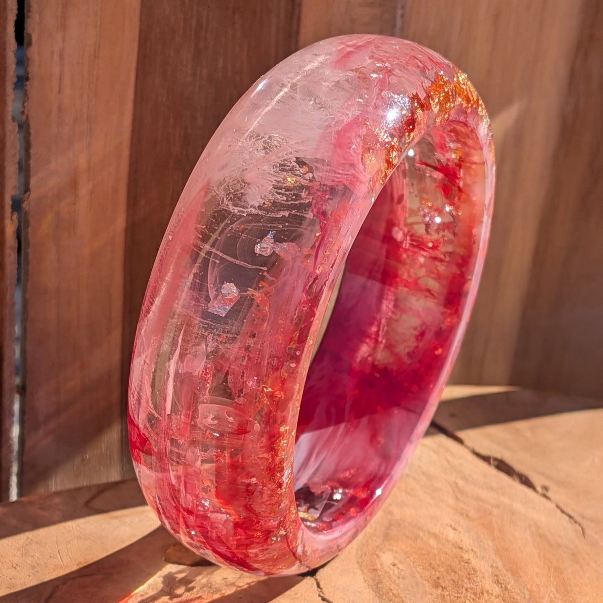 Chunky pink and red resin dome bangle with gold copper silver flakes flat lay on wooden surface – EL-Creations