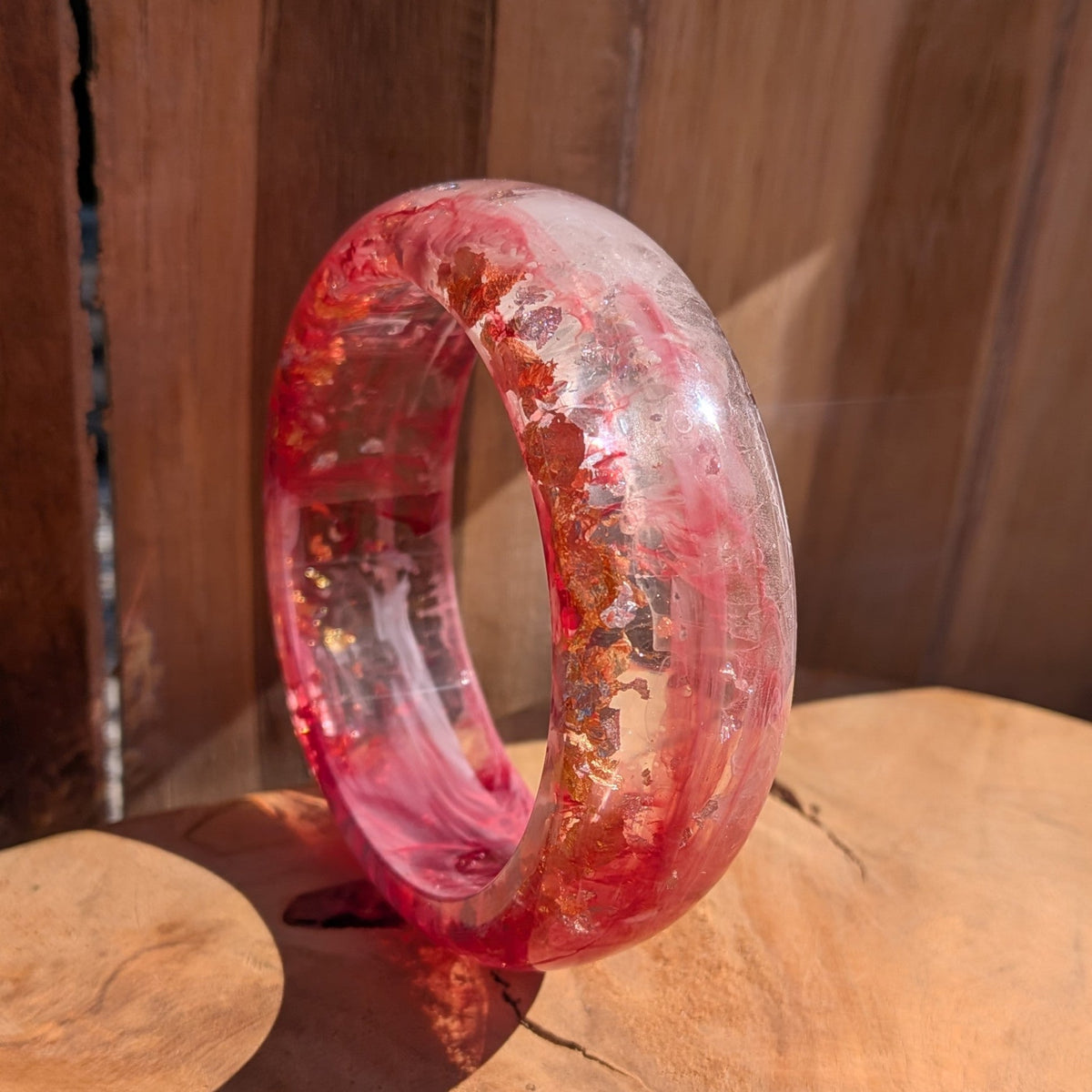 Bold pink resin dome bangle close-up showing gold copper silver flake detail and polished surface on wood – EL-Creations