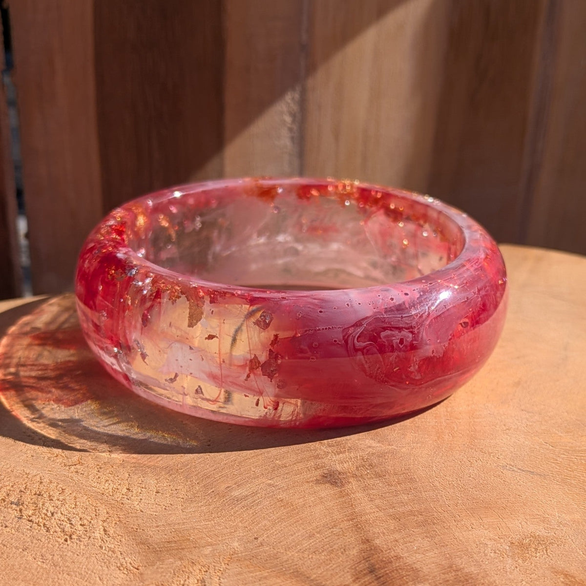 Pink and red resin slip-on bangle 5mm thickness side profile on wooden surface showing dome shape – EL-Creations