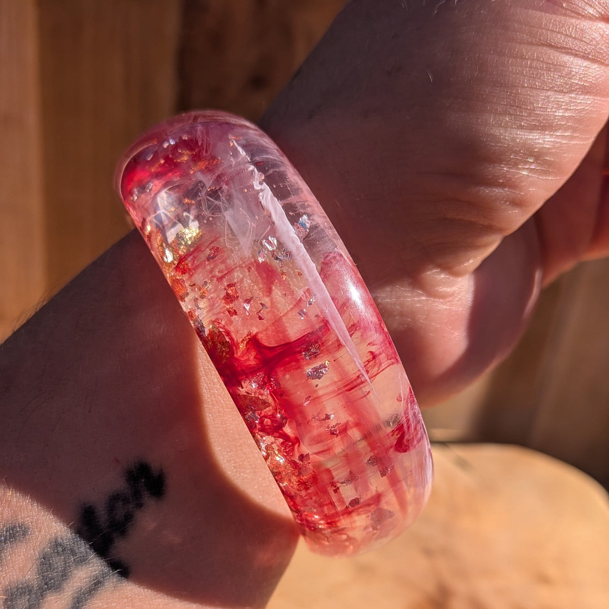 Chunky dome resin bangle pink red pigment with silver copper gold flakes close-up showing depth on wood – EL-Creations