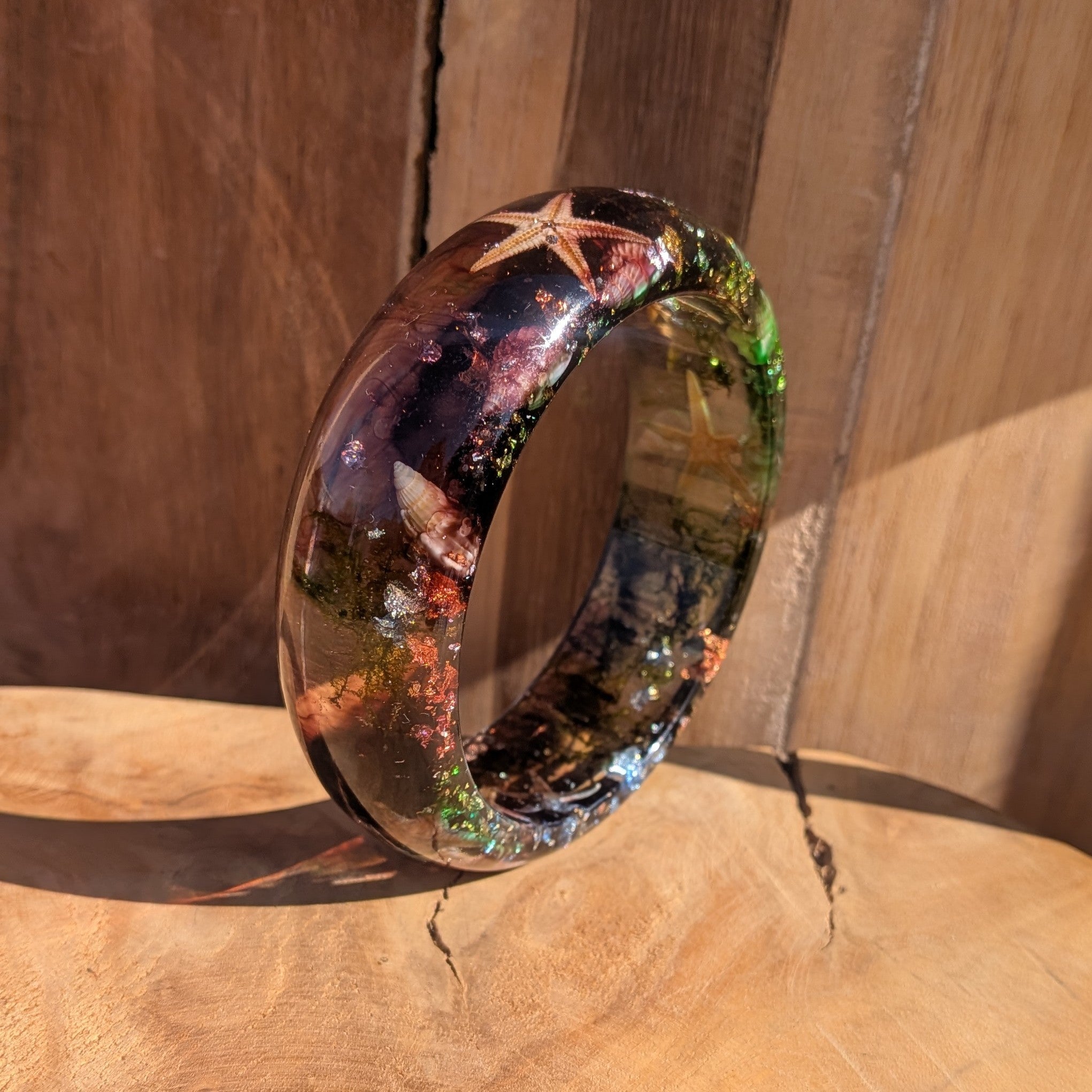 Clear resin bangle with dried starfish and sea moss close-up showing gold copper silver flake detail – EL-Creations