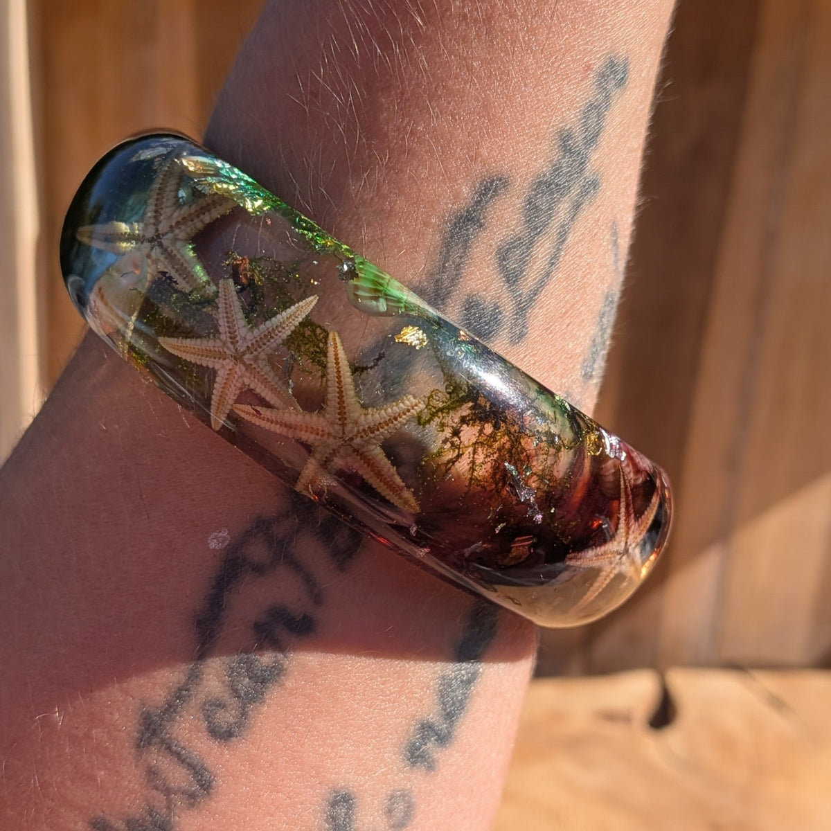 Handmade clear resin bangle with real starfish seashells and sea moss with gold copper silver flakes top view on wood – EL-Creations