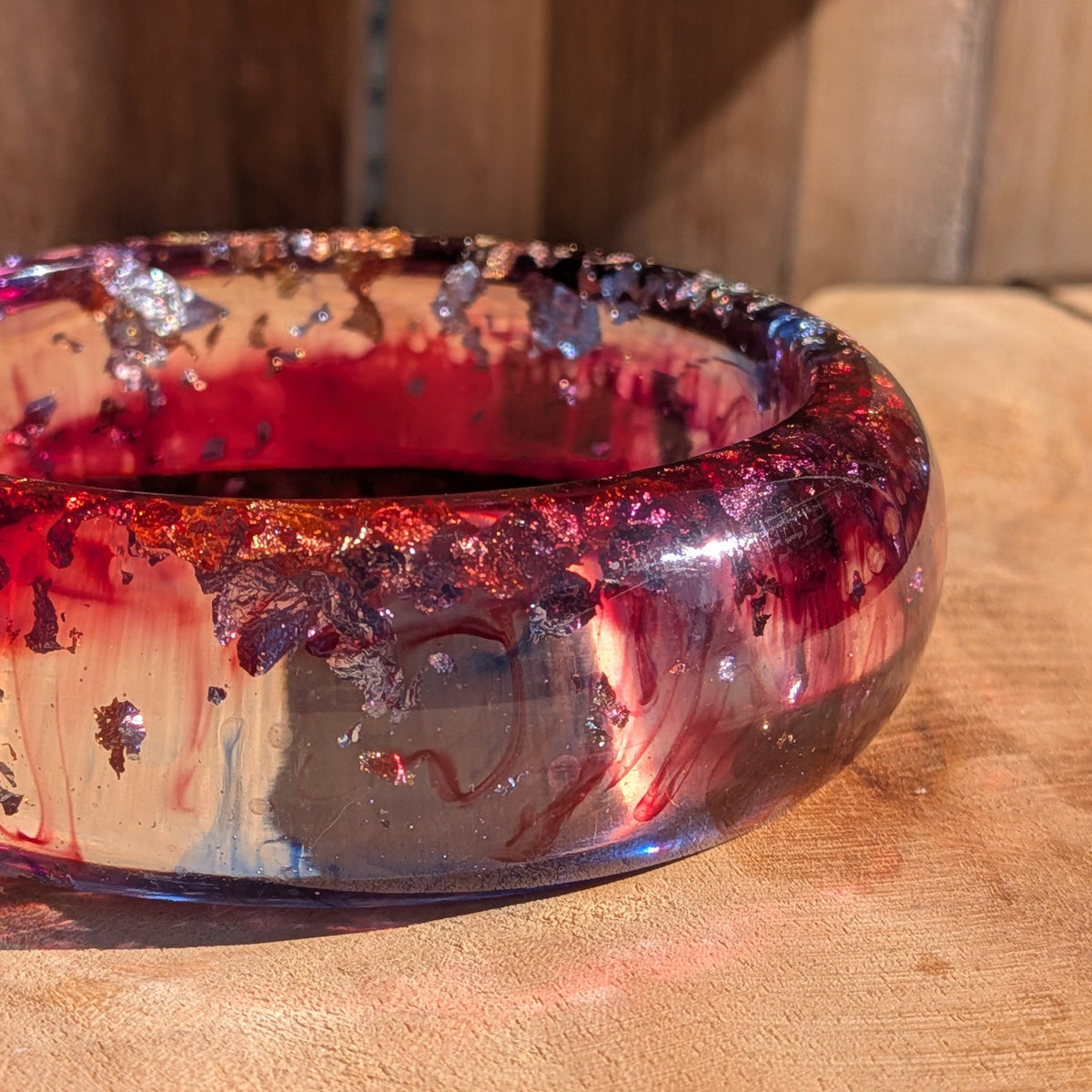 Wide crimson violet resin slip-on bangle flat lay showing swirling pigment and metallic flakes on wood – EL-Creations