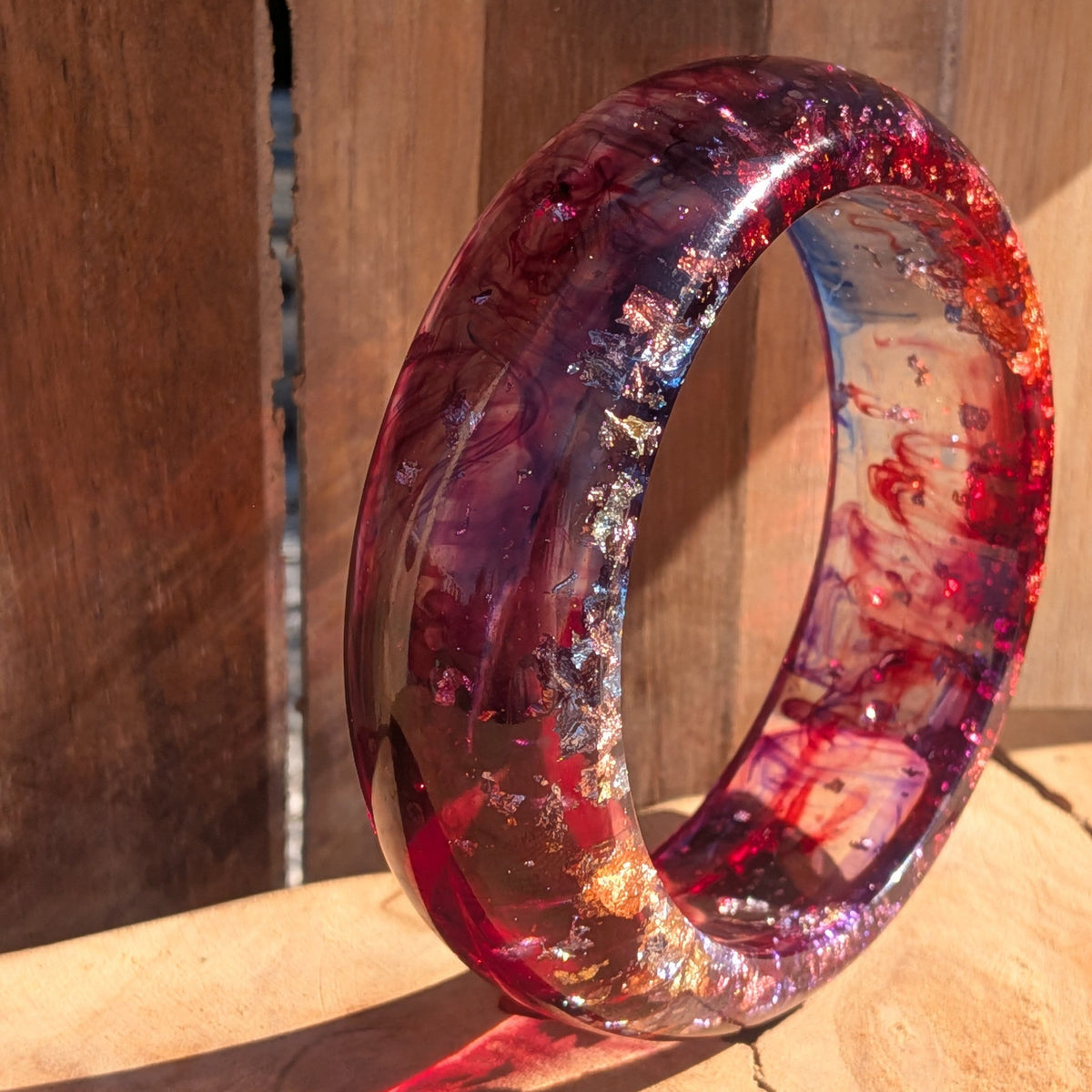 Handmade resin bangle crimson and violet pigment swirls with silver copper gold flakes worn on wrist side view – EL-Creations