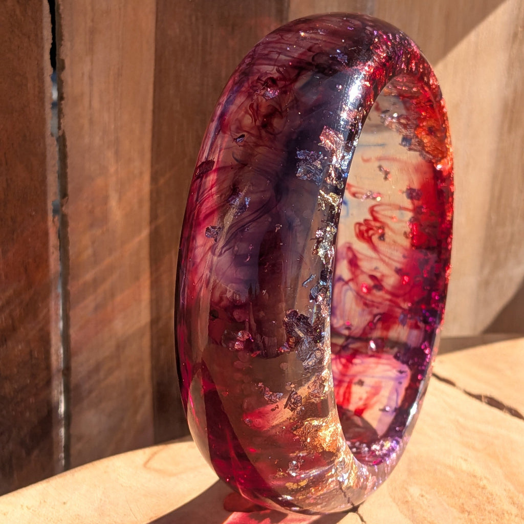 Bold red resin bangle worn on tattooed wrist showing full width and dramatic colour depth outdoor – EL-Creations
