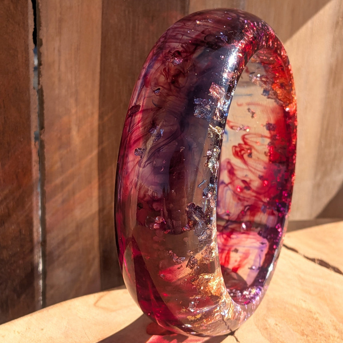 Bold red resin bangle worn on tattooed wrist showing full width and dramatic colour depth outdoor – EL-Creations