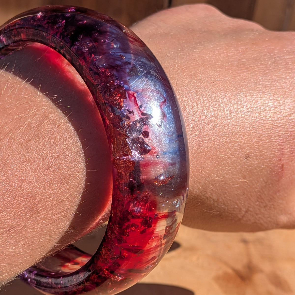Wide resin bangle 23mm crimson violet pigment worn on wrist front view showing sculptural silhouette – EL-Creations