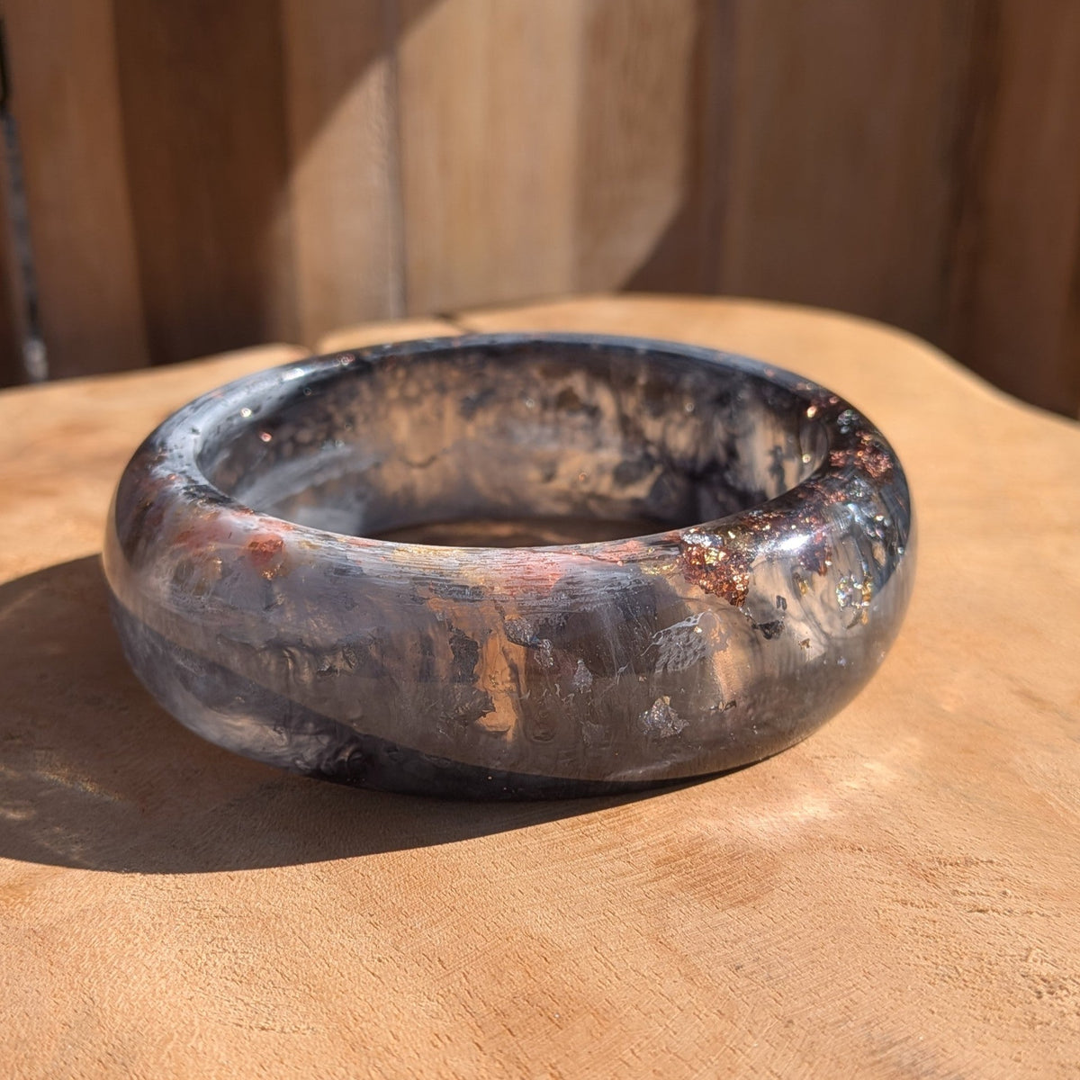 Chunky black and white resin dome bangle with gold copper silver flakes worn on wrist front view outdoor – EL-Creations