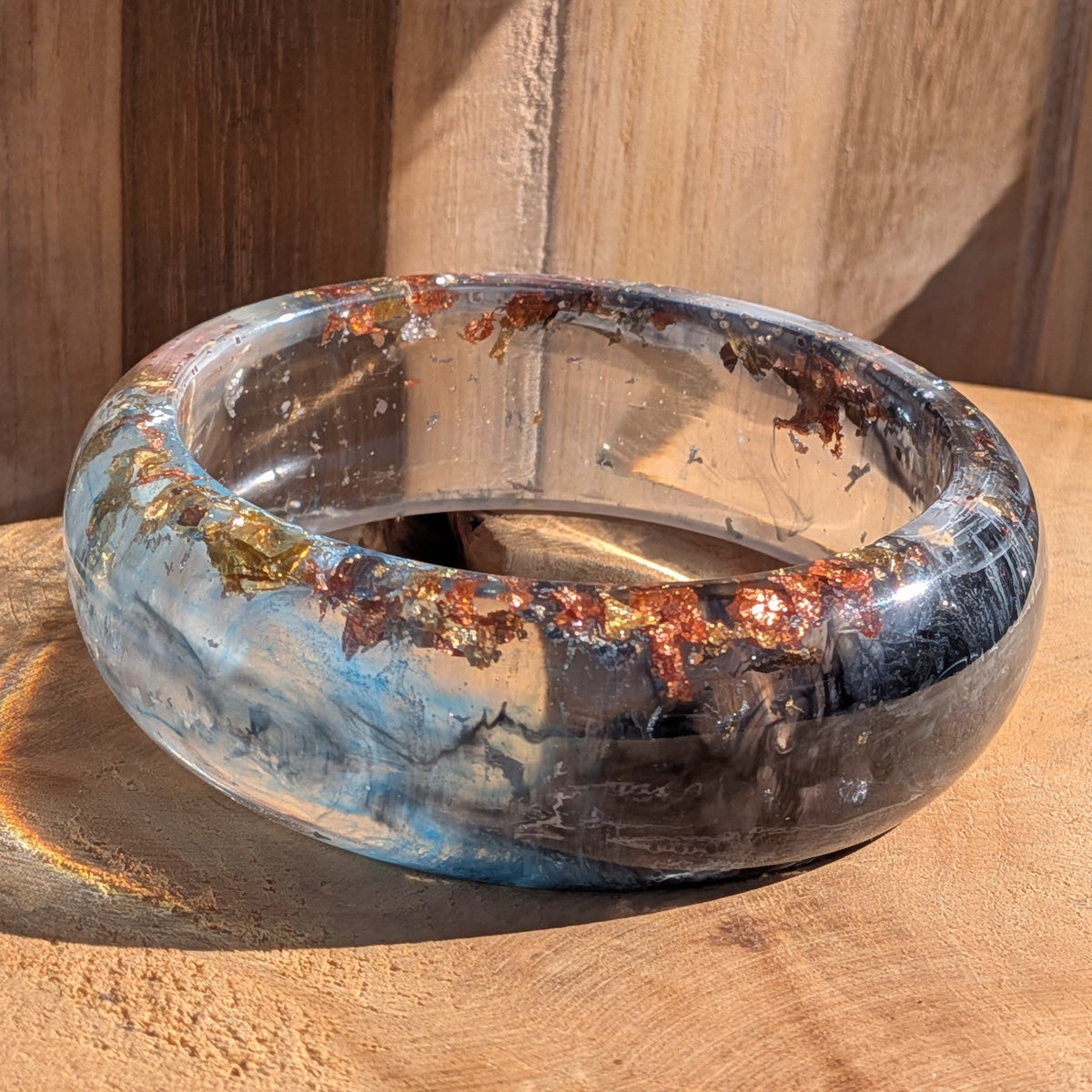 Blue resin statement bangle standing upright showing navy and black pigment swirls on wooden surface – EL-Creations