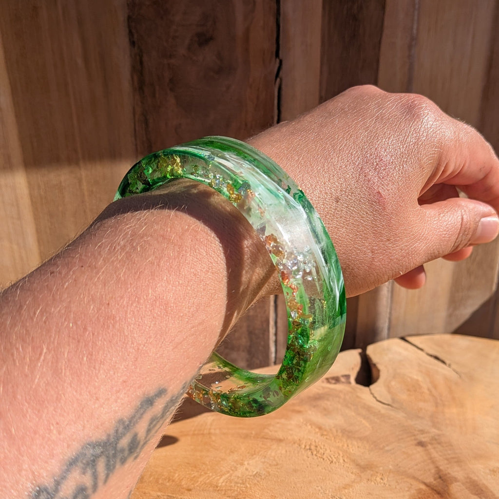 Handmade green resin bracelet with swirling pigment and metallic flakes worn on wrist outdoor – EL-Creations