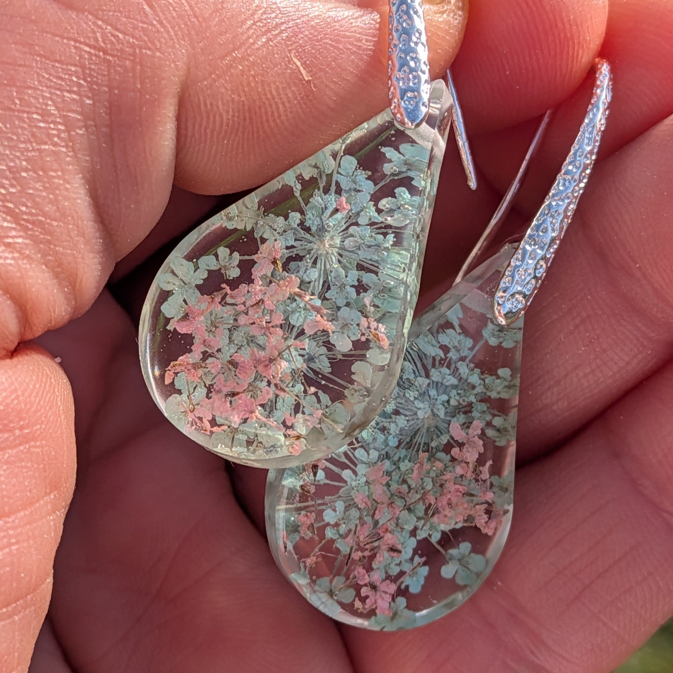 Queen Anne's Lace resin earrings held in hand showing teardrop shape and flower detail – EL-Creations