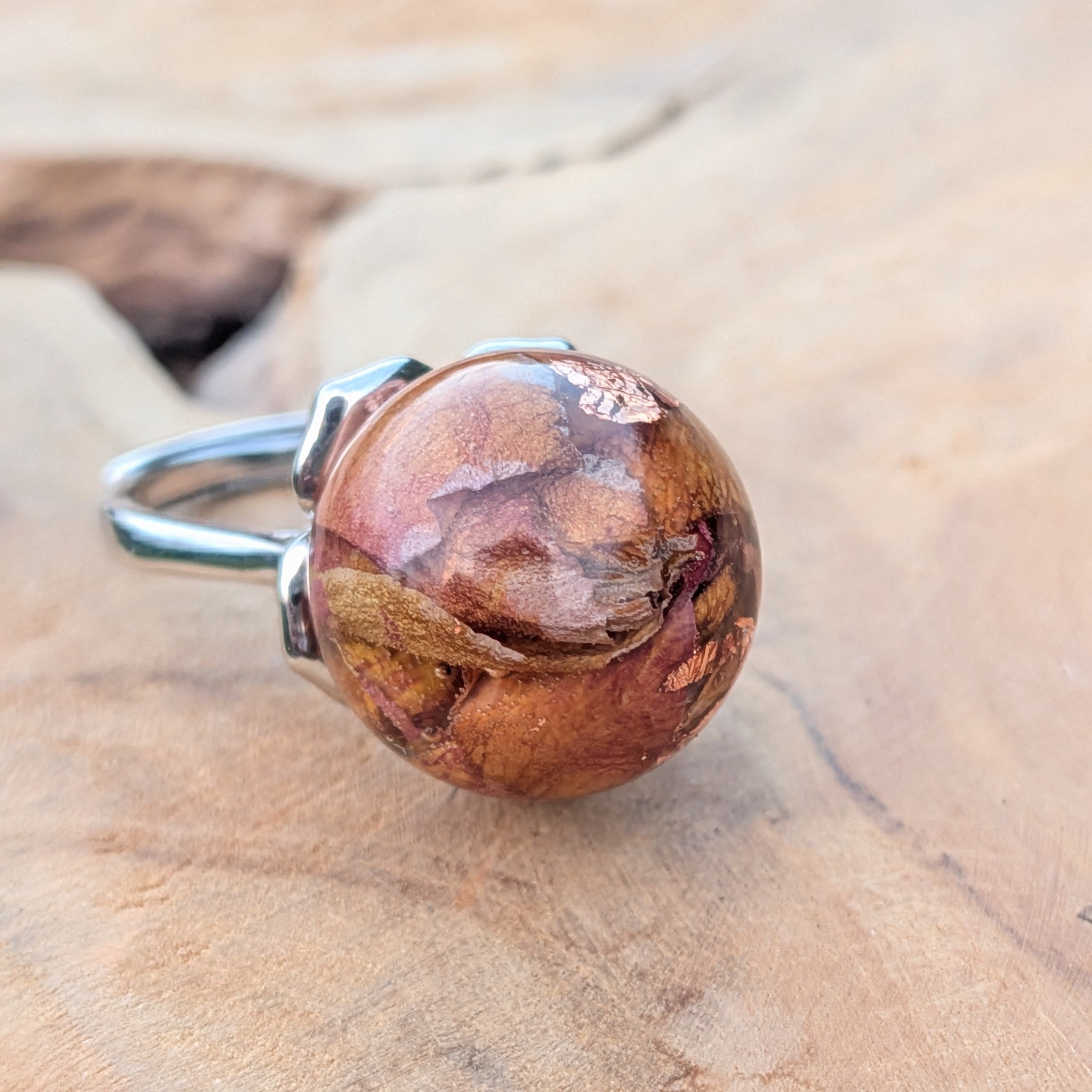 Macro close-up of resin sphere ring with rose petals and copper flakes – amber tones – EL-Creations