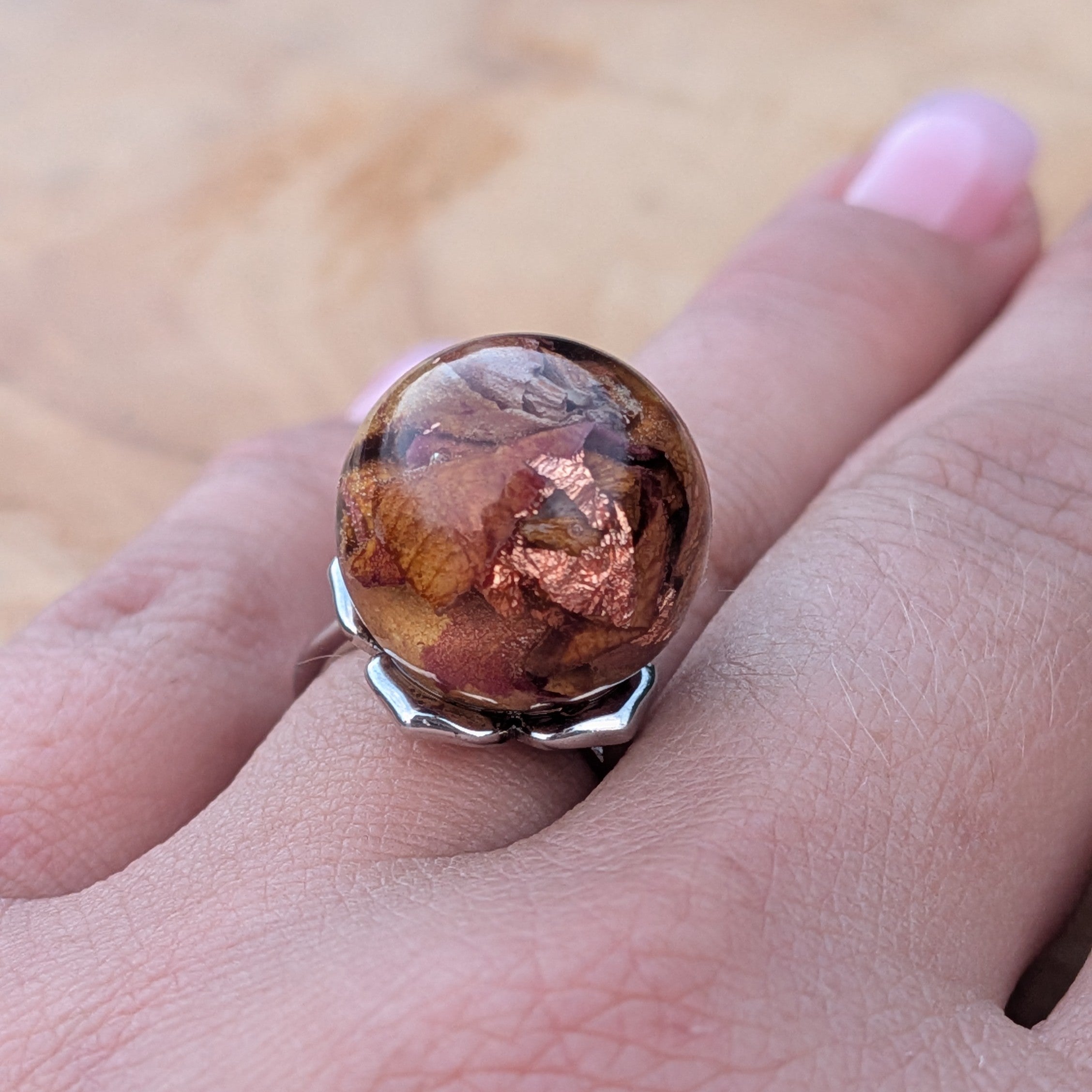 Silver adjustable resin ring with rose petals and copper flakes worn on hand outdoors – EL-Creations