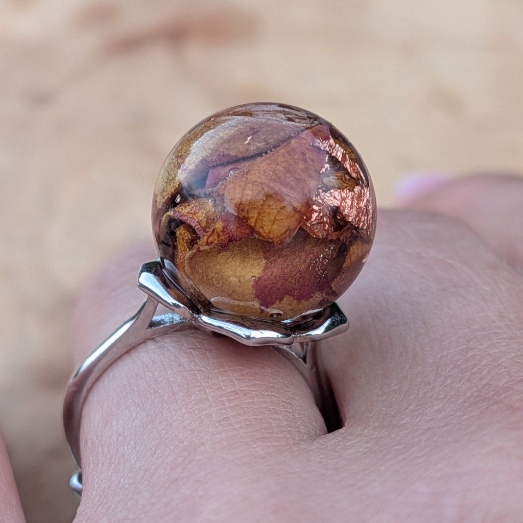 Macro focus shot of resin sphere with rose petals and copper flakes inclusions – EL-Creations