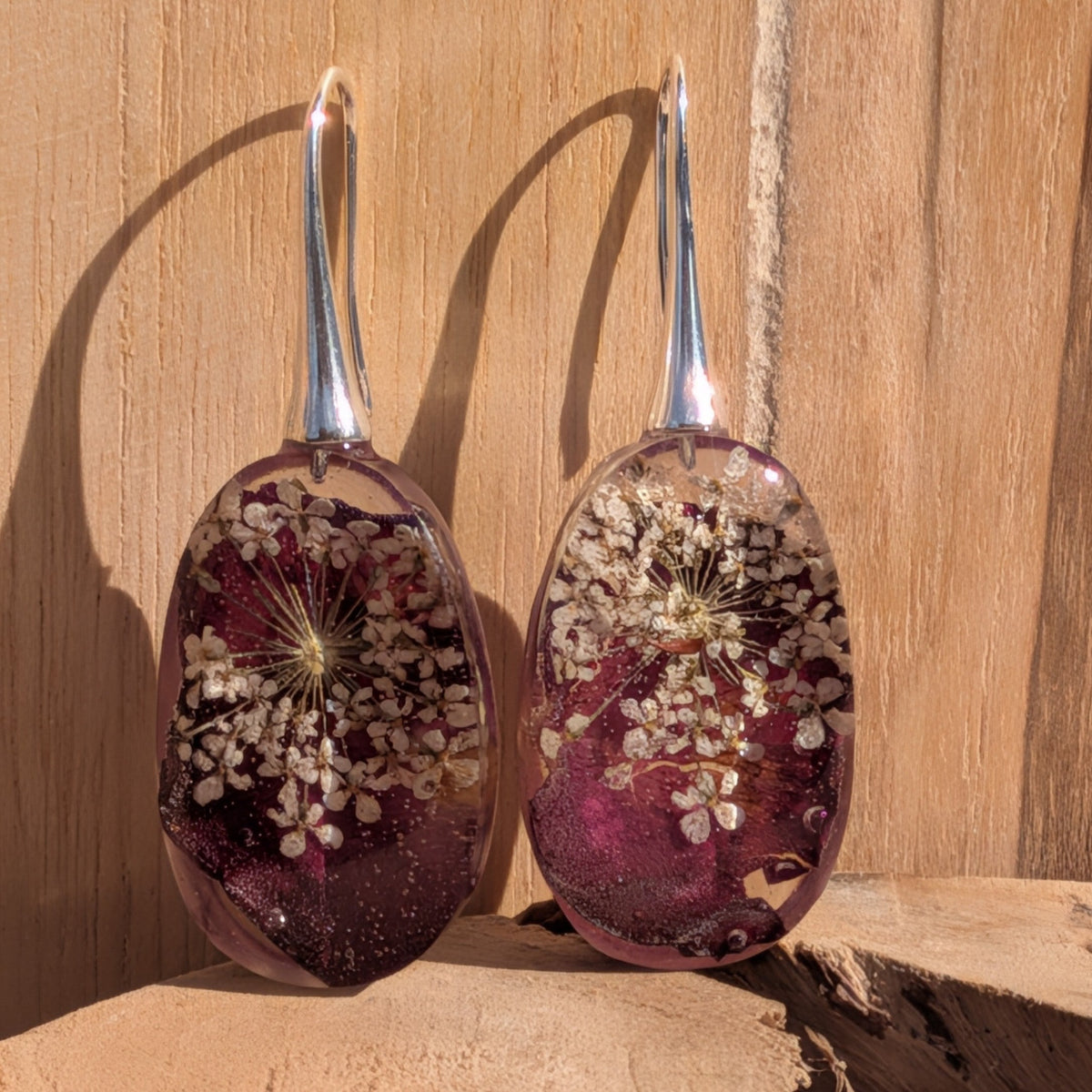 Close-up of dried flower resin earrings showing white lace detail on deep red base – EL-Creations