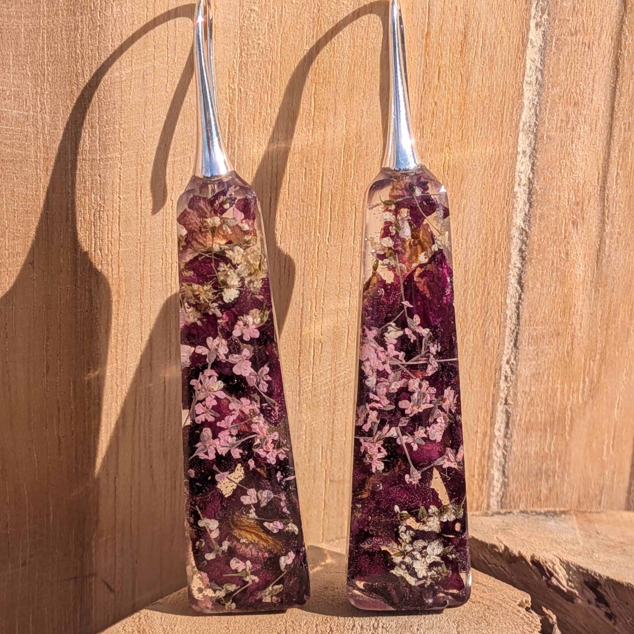 Rose petals and Queen Anne's Lace resin earrings – leaning against wooden wall in sunlight – EL-Creations