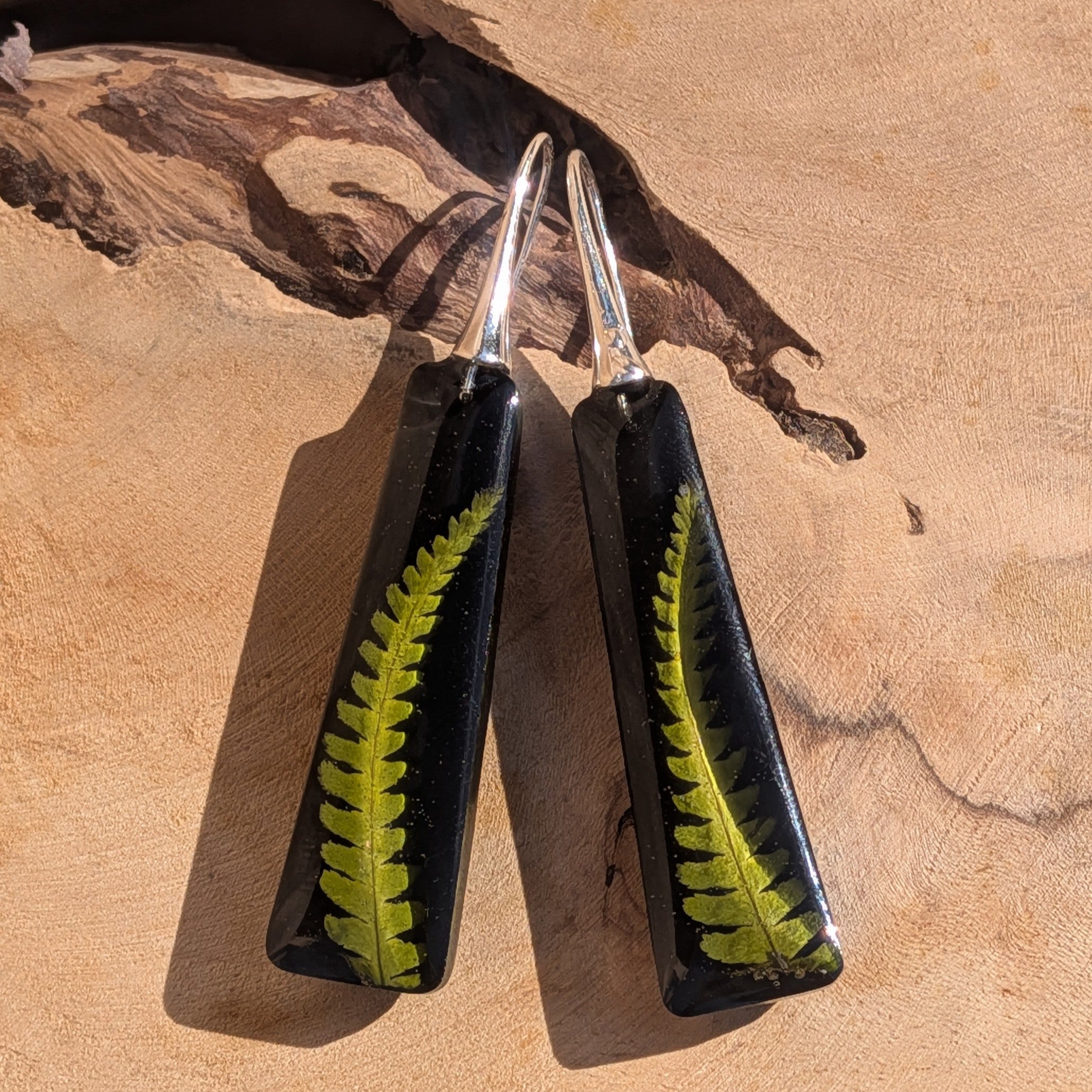 Botanical black resin earrings with real fern frond – pair on wooden surface – EL-Creations