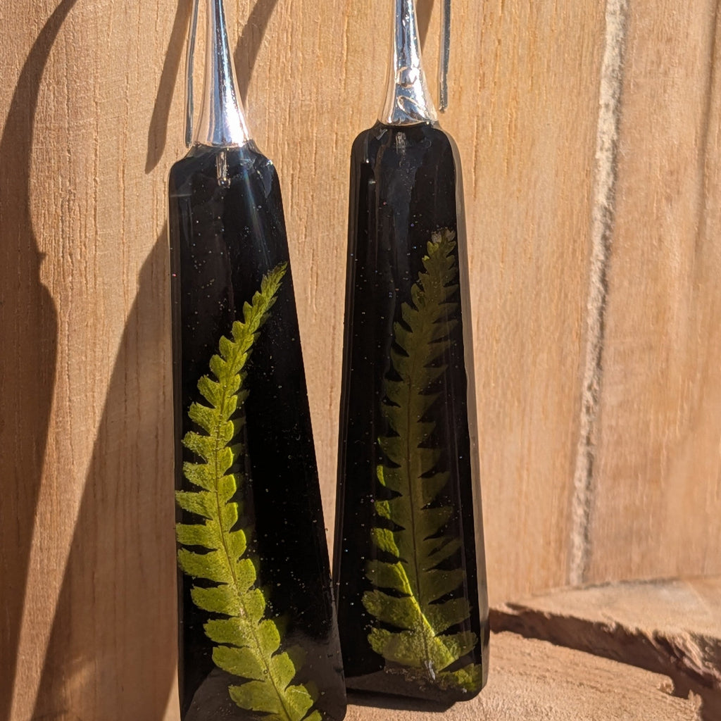 Handmade black resin fern earrings with silver hooks on driftwood – front view – EL-Creations