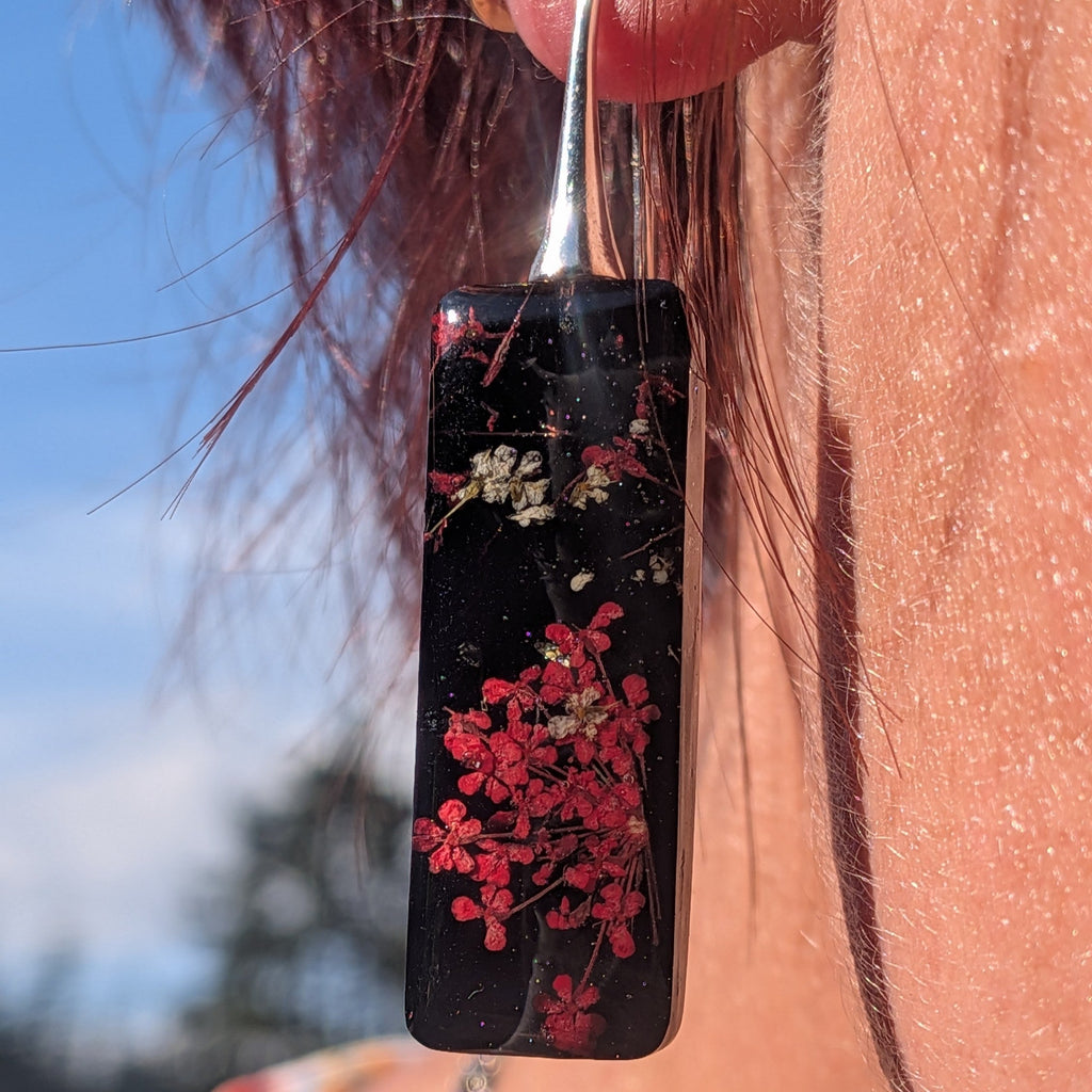 Black resin dangle earrings with red Queen Anne's Lace and white baby's breath on wooden surface – EL-Creations