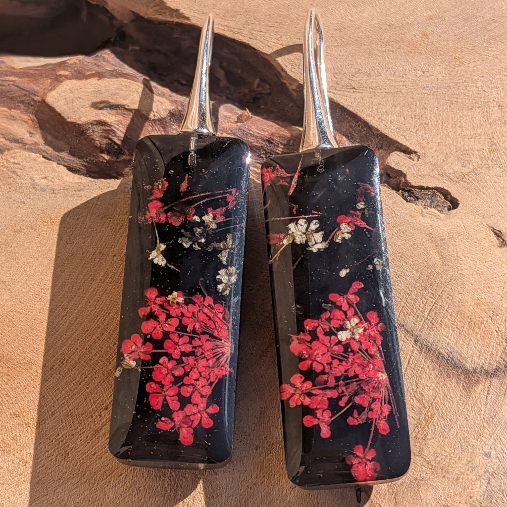 Handmade black resin dangle earrings with Queen Anne's Lace – close-up on wooden surface – EL-Creations