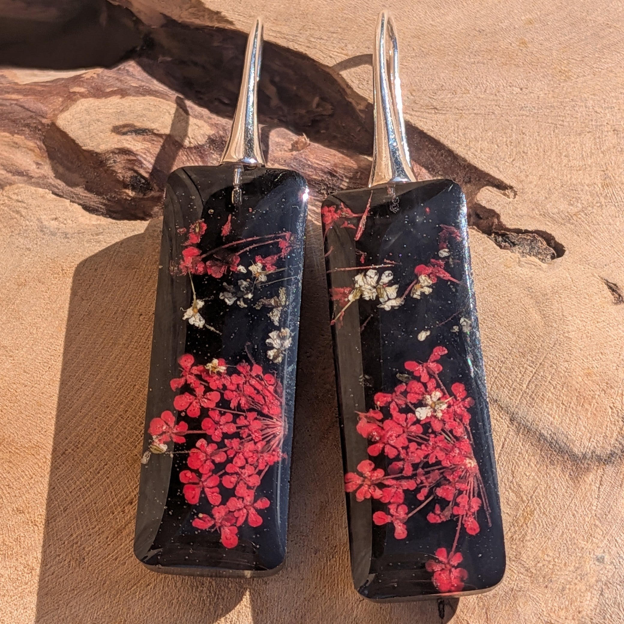 Handmade black resin dangle earrings with Queen Anne's Lace – close-up on wooden surface – EL-Creations