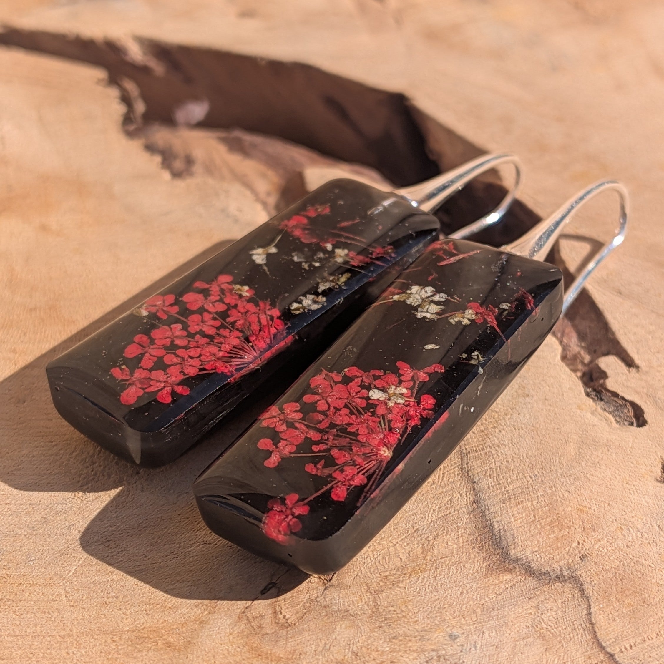 Handmade black resin earrings with dried red Queen Anne's Lace flowers – front view on wood – EL-Creations