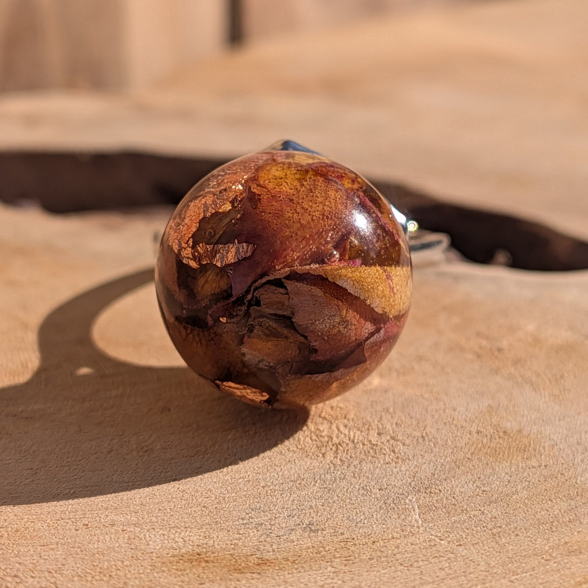 Close-up of 15mm resin sphere ring with rose petals and copper flakes, warm amber tones, silver adjustable ring – EL-Creations
