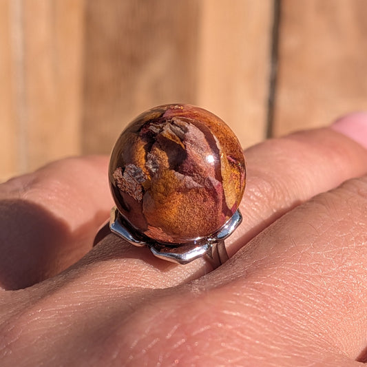 Handmade resin globe ring with real dried rose petals and copper flakes, silver adjustable band, held in palm – EL-Creations